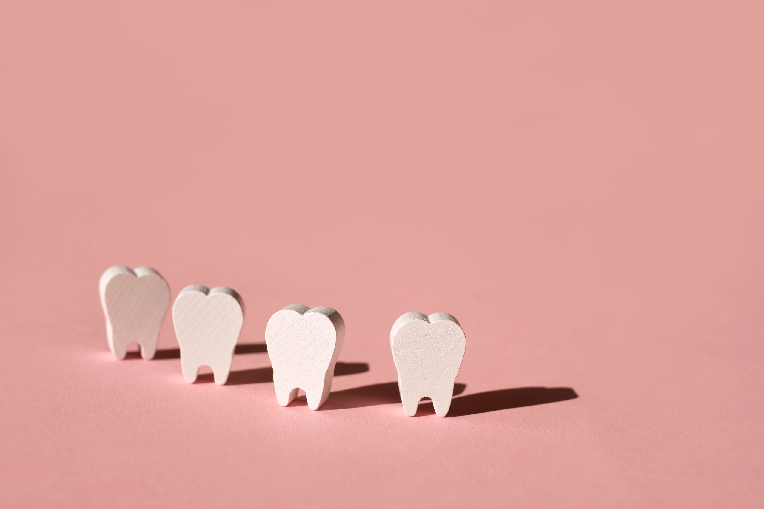 Teeth stand in a row on a pink background with a deep shadow